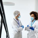 female doctors with face masks discussing about patient s medical data hospital lobby