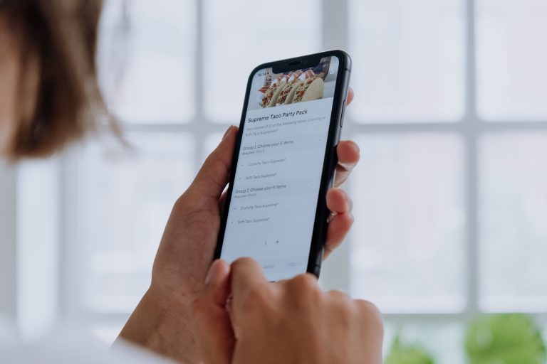 iOS 27 Brings AI-Powered Photo Tools and Faster Performance to iPhone 2 Close-up of hands using a smartphone to order food online through an app, showcasing modern technology