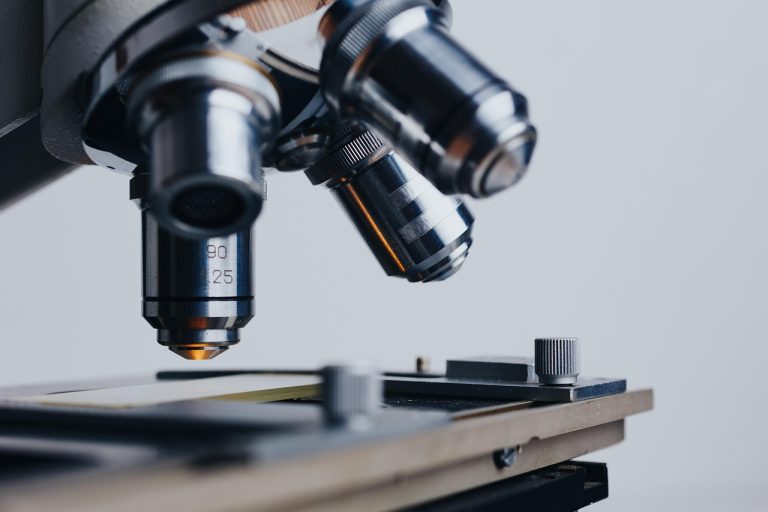 Close-up of a microscope with objective lenses positioned over a laboratory slide specimen