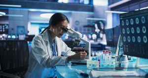 A laboratory researcher examines a sample through a microscope