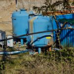 Outdoor industrial water filtration plant with large blue tanks under sunlight