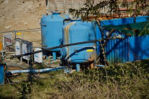 Outdoor industrial water filtration plant with large blue tanks under sunlight